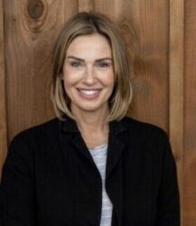 a woman smiles at the camera while standing in front of a wood paneled wall