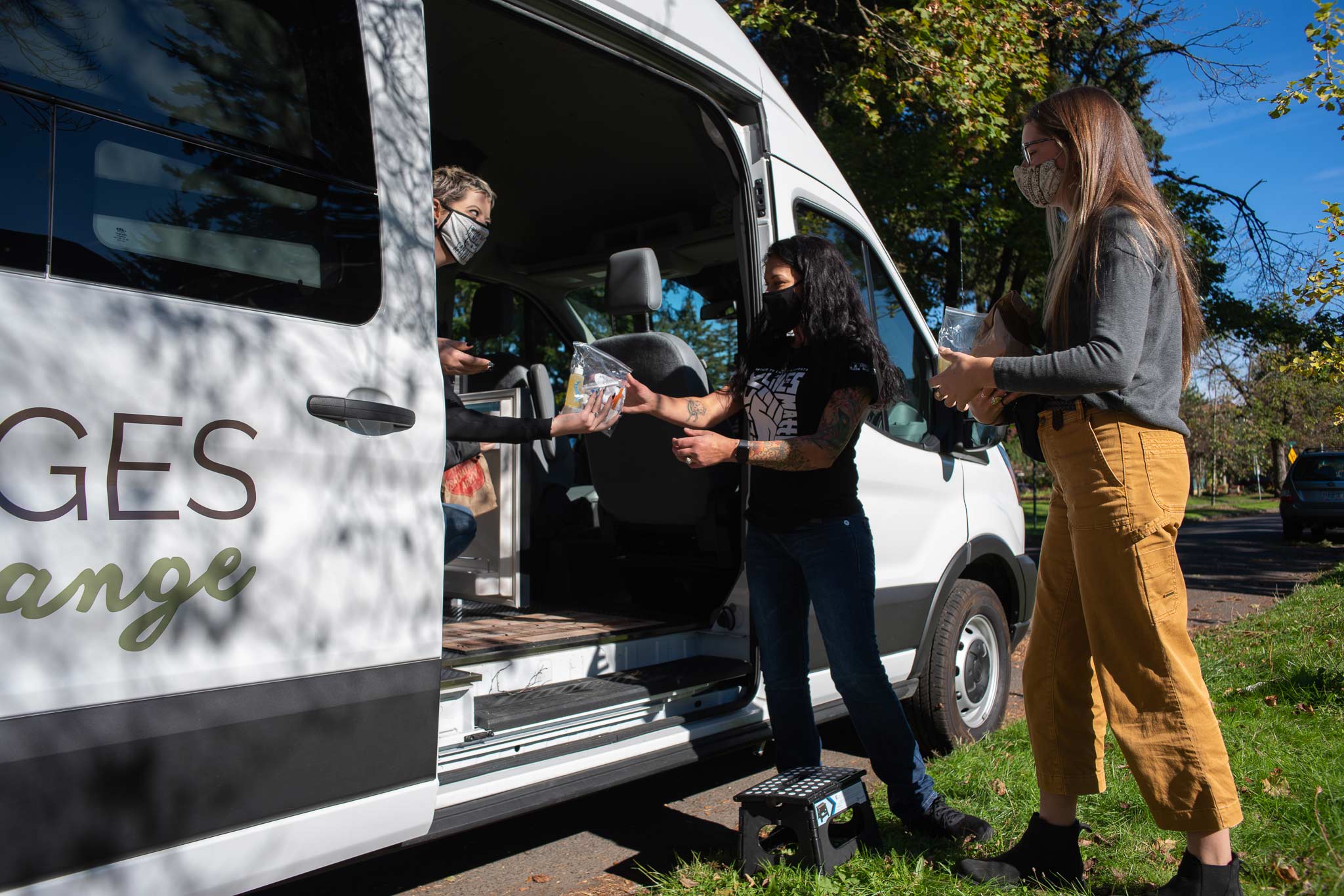 a person standing in the bridges to change community outreach sprinter van hands another person a ziplock bag of supplies