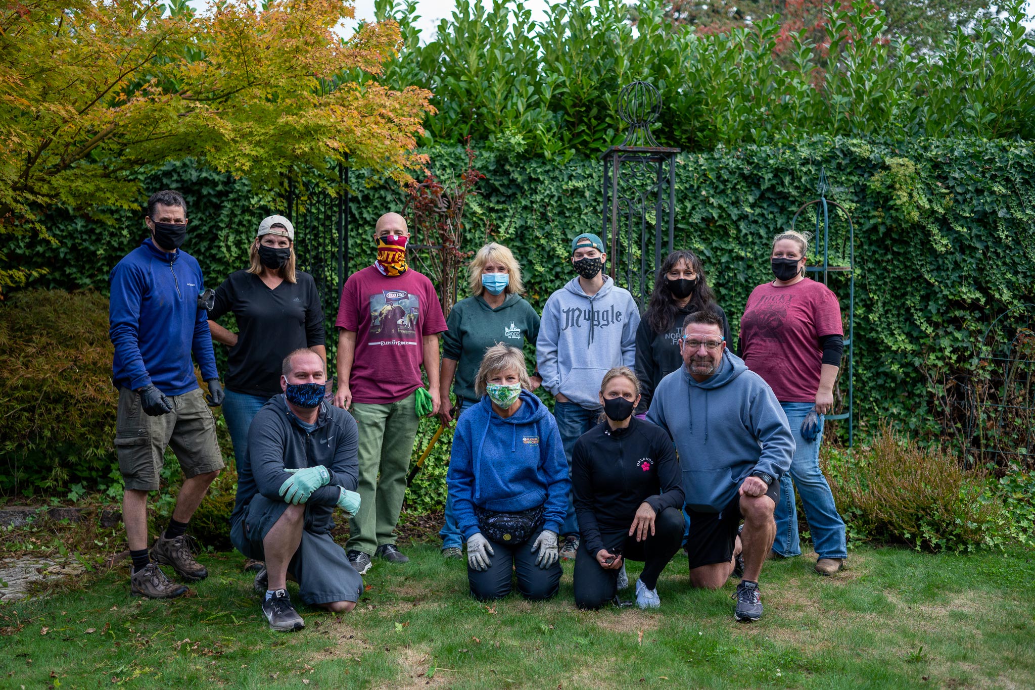 a masked group of people kneeling and standing for a group photo