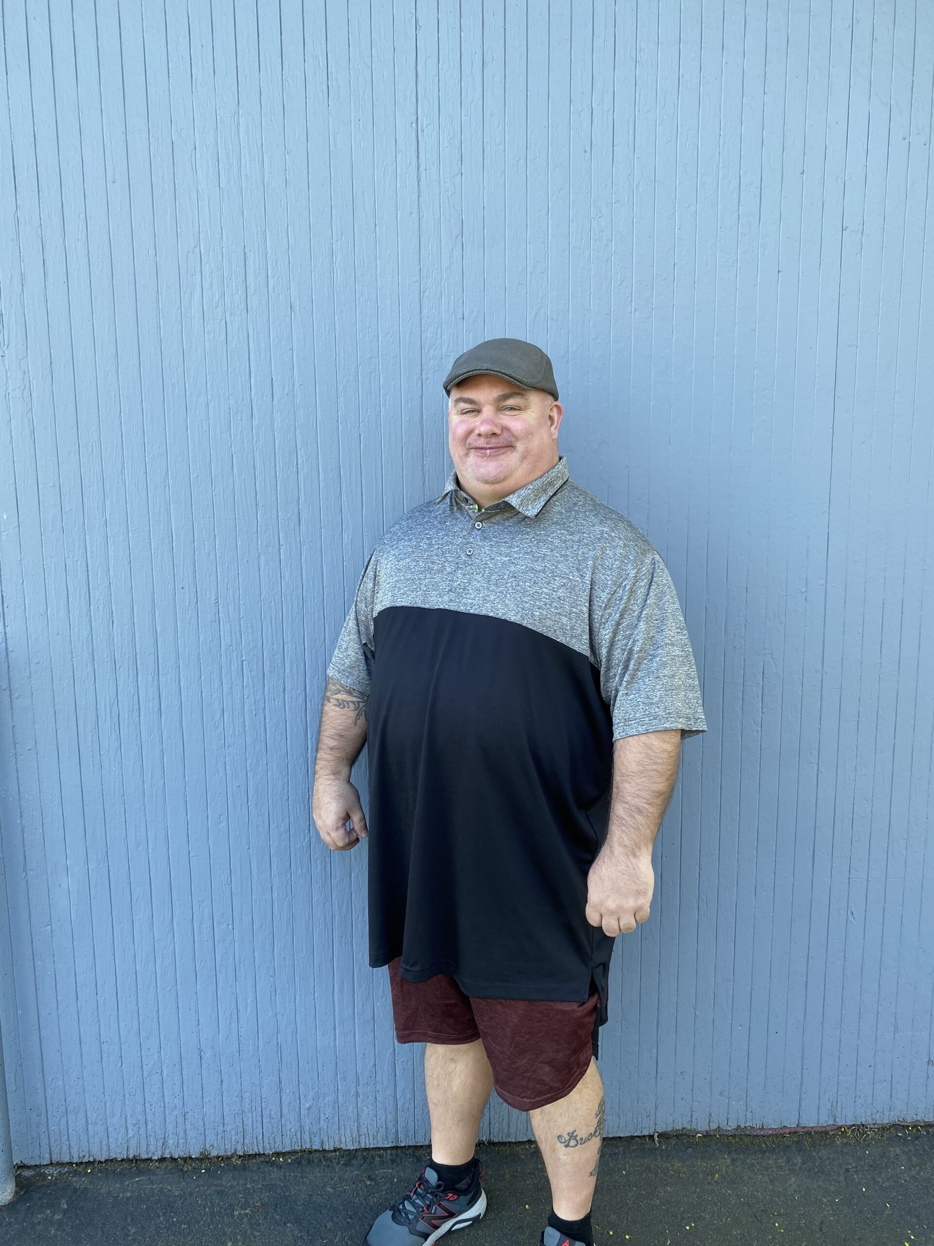 a smiling man with his back against a periwinkle blue wall